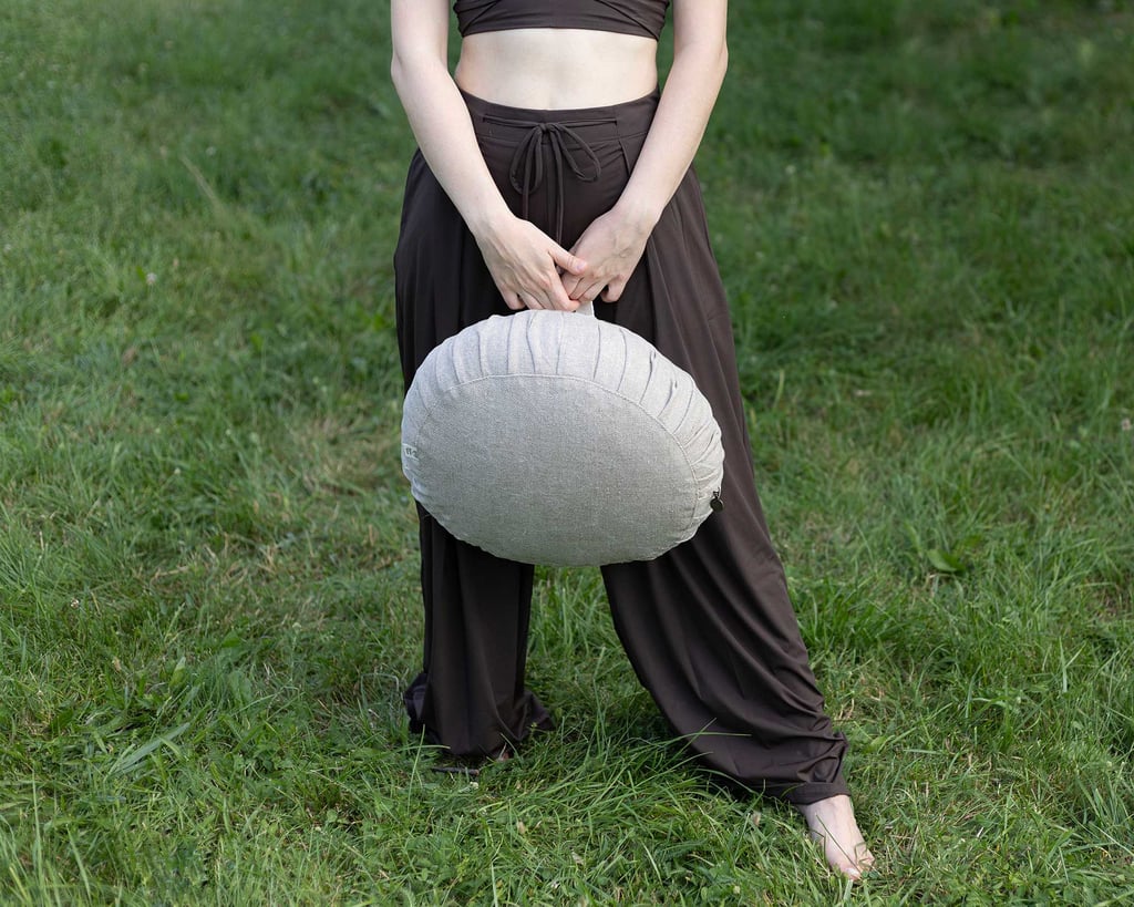 girl holding a meditation wool cushion in the park