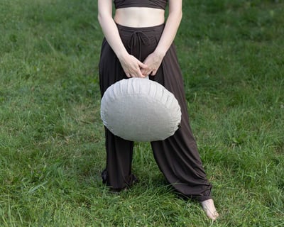 girl holding a meditation wool cushion in the park