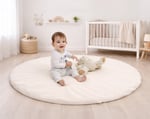 baby playing on a round wool play mat