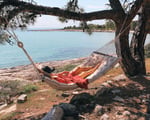 woman lying on a wool hammock by the sea