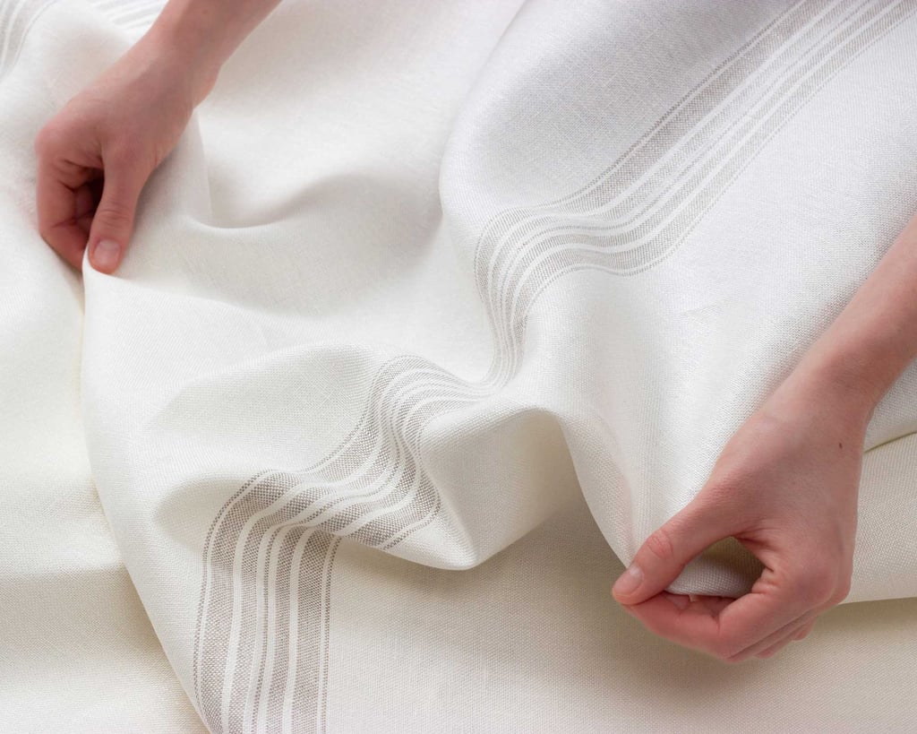 grey striped linen fabric being folded and held by hands