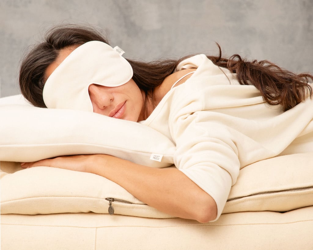 Femme allongée sur un matelas en laine, portant un masque de sommeil en soie de mûrier.