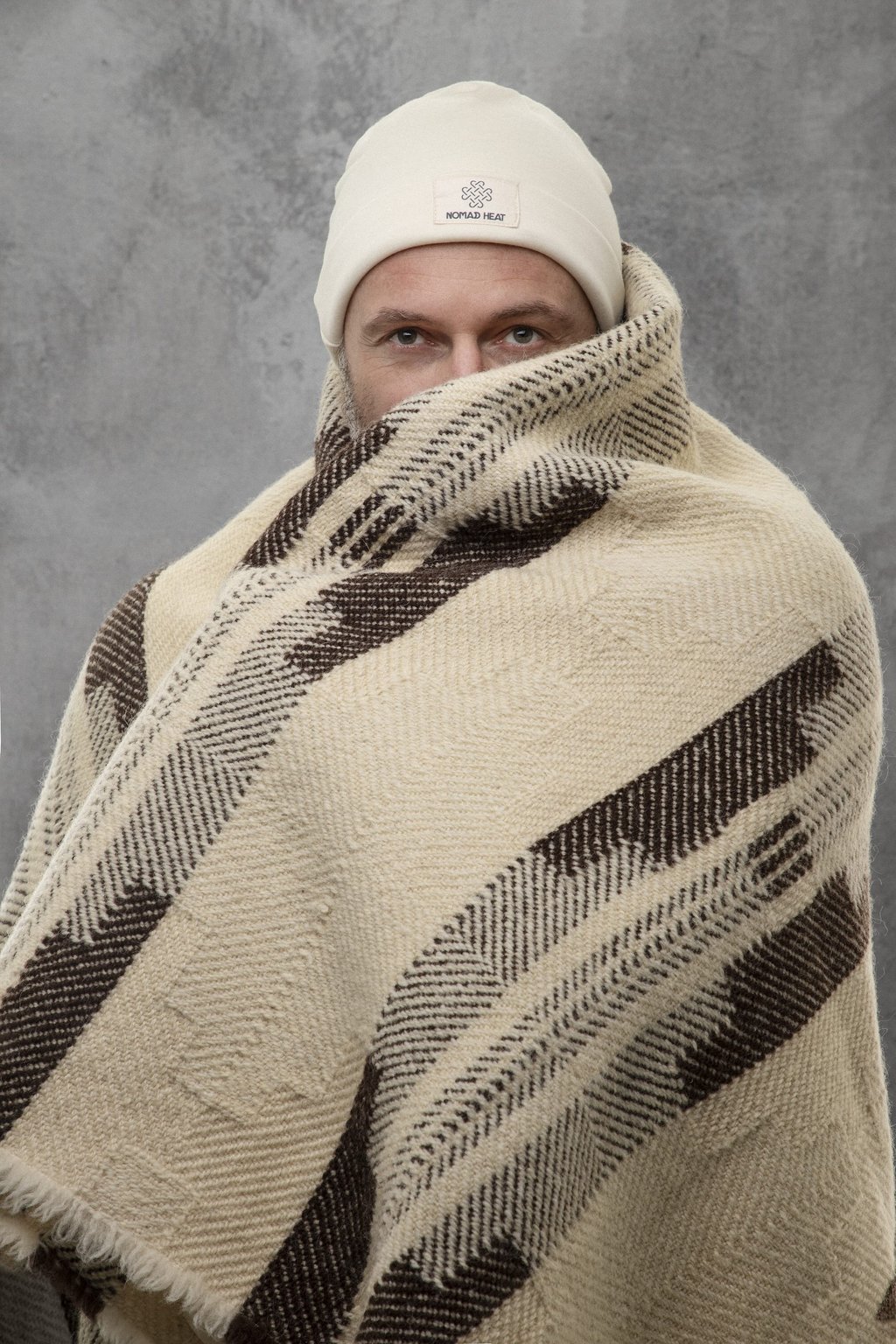man wrapped in nomad heat heavy wool blanket