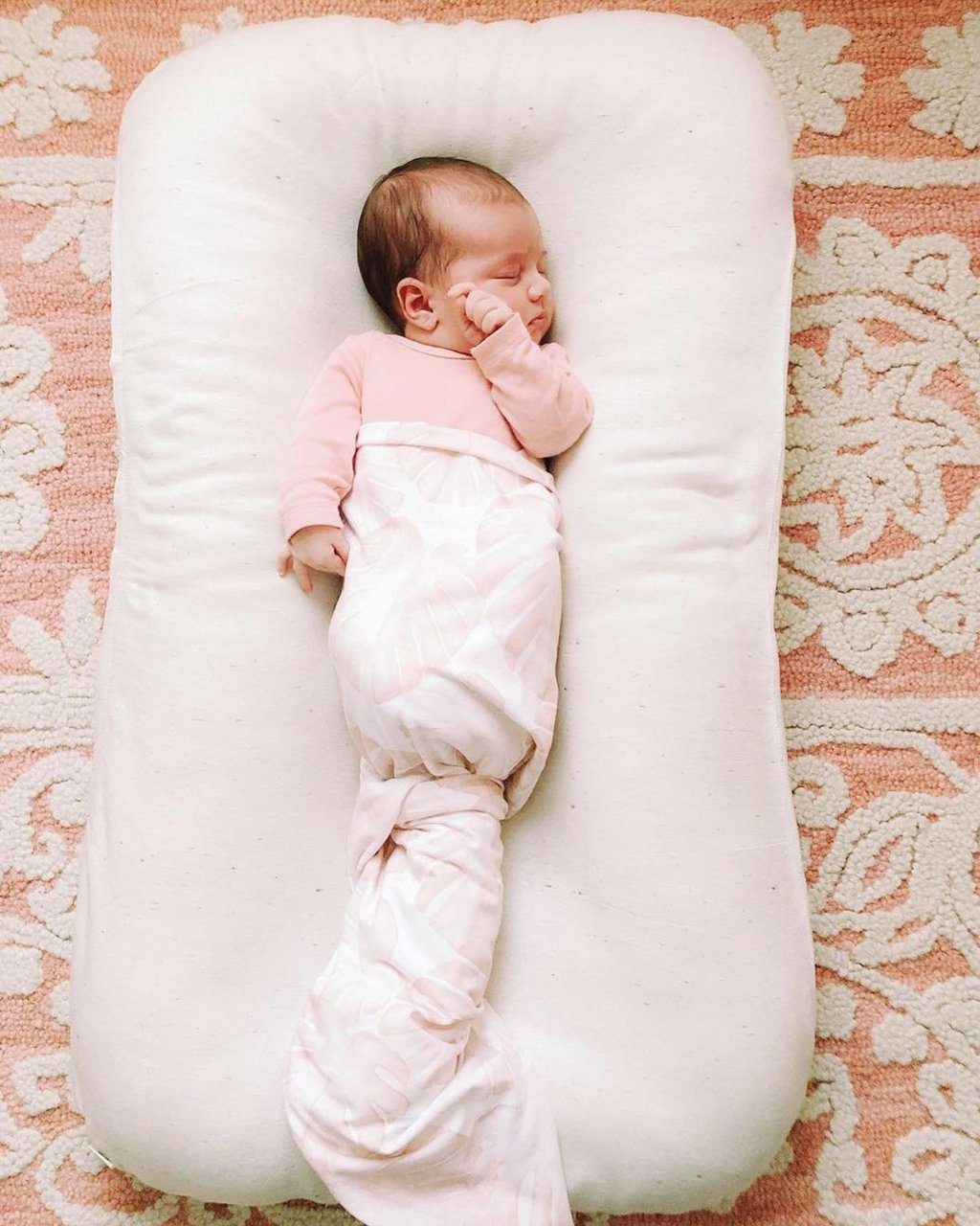 top full view of a baby sleeping in a wool baby lounger