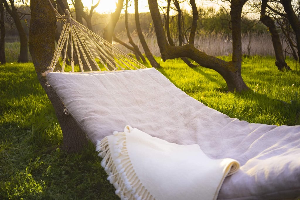 natural wool hammock cushion with a cream throw in a sunlit garden