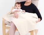 mom holding baby covered with wool saddle blanket