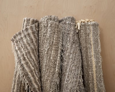 Four zero waste linen handwooven rugs on wooden wall