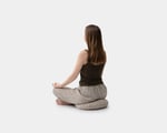 a girl sitting on a wool zafu yoga cushion