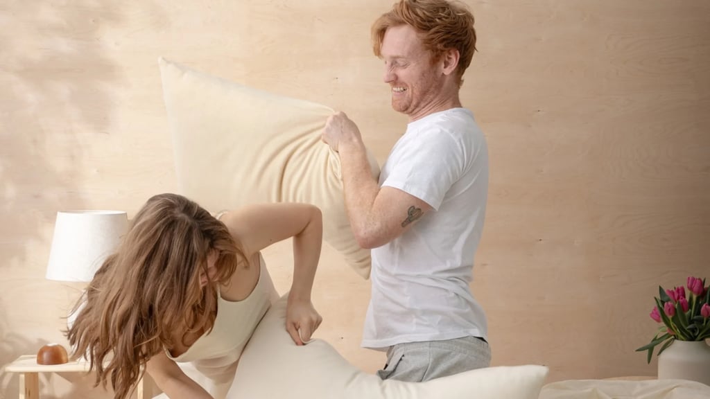 man and woman pillow fighting with home of wool pillows