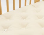 detail of the tufts of a home of wool oval crib mattress for stokke sleepi
