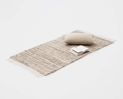 Cojín decorativo sobre alfombra de lino tejida a mano.