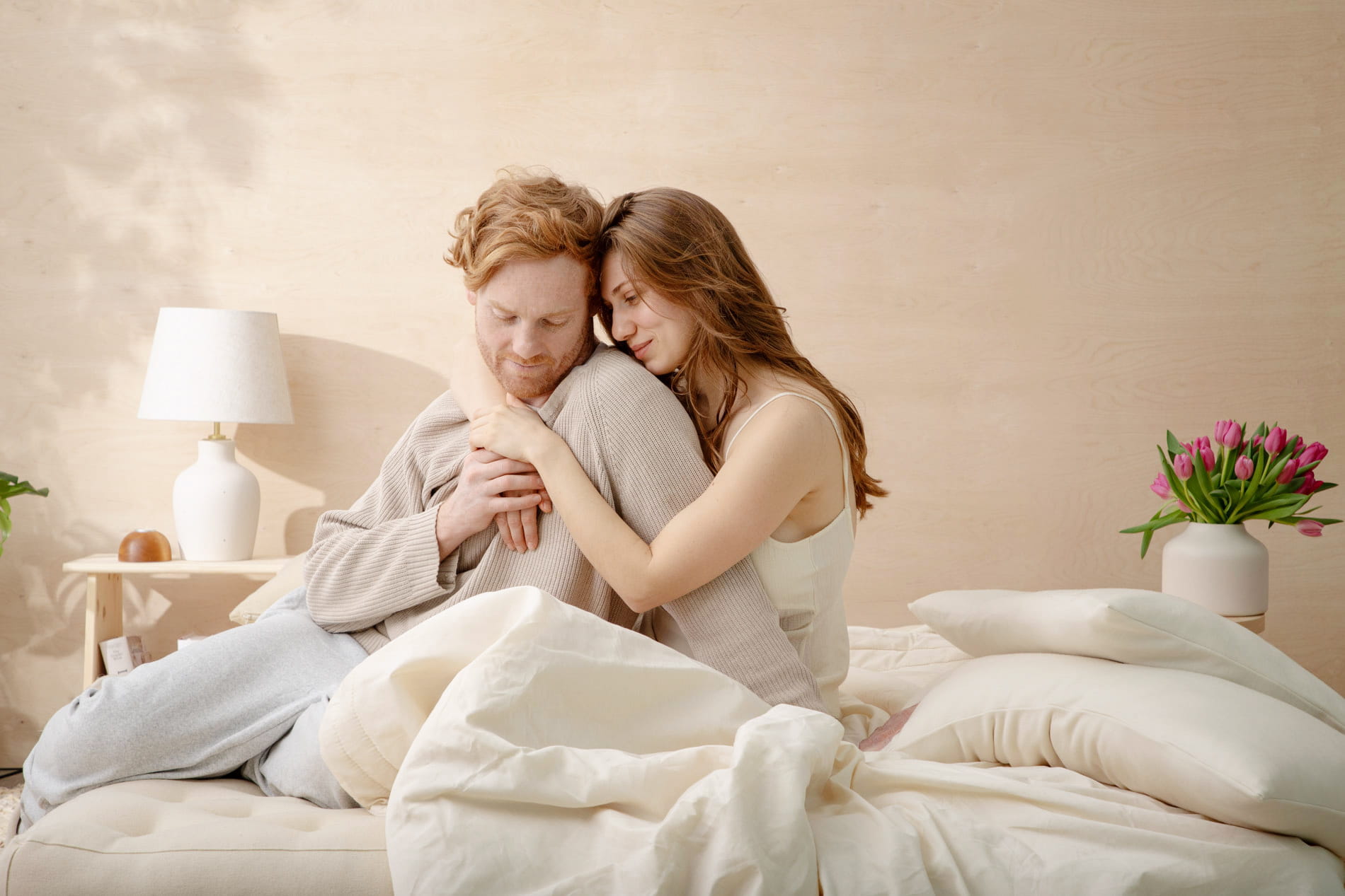 couple embracing on a tufted mattress with bedding