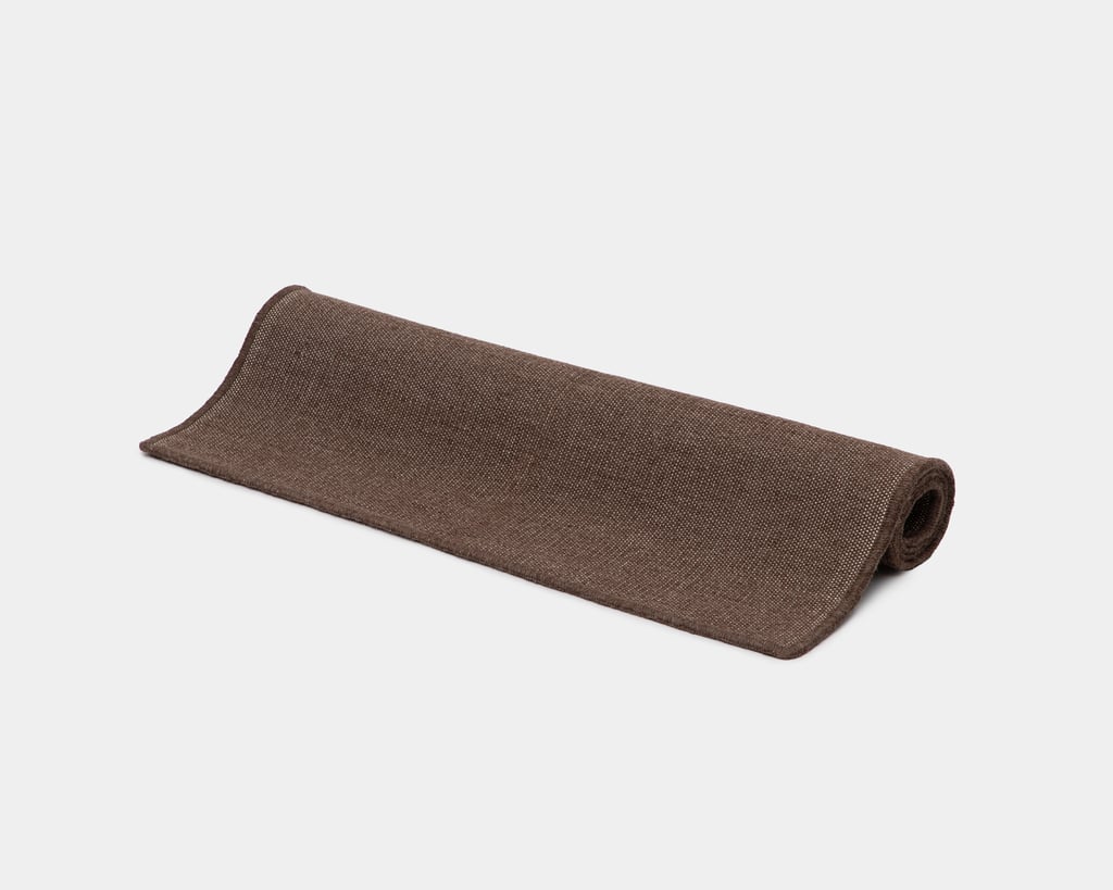 flat woven rug rolled up in natural brown color