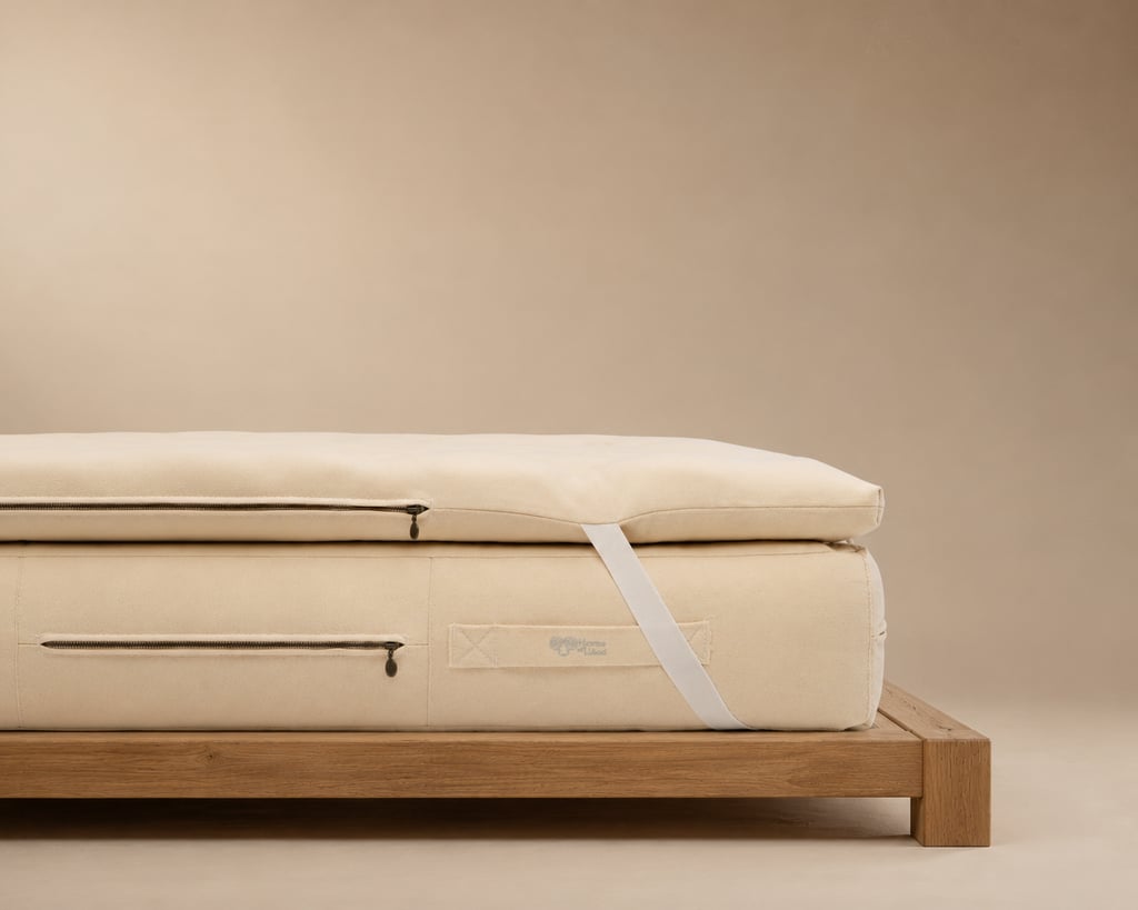 Cream mattress topper secured to a mattress with a white elastic corner strap.