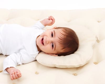 baby lying on a baby wool pillow on a baby wool mattress