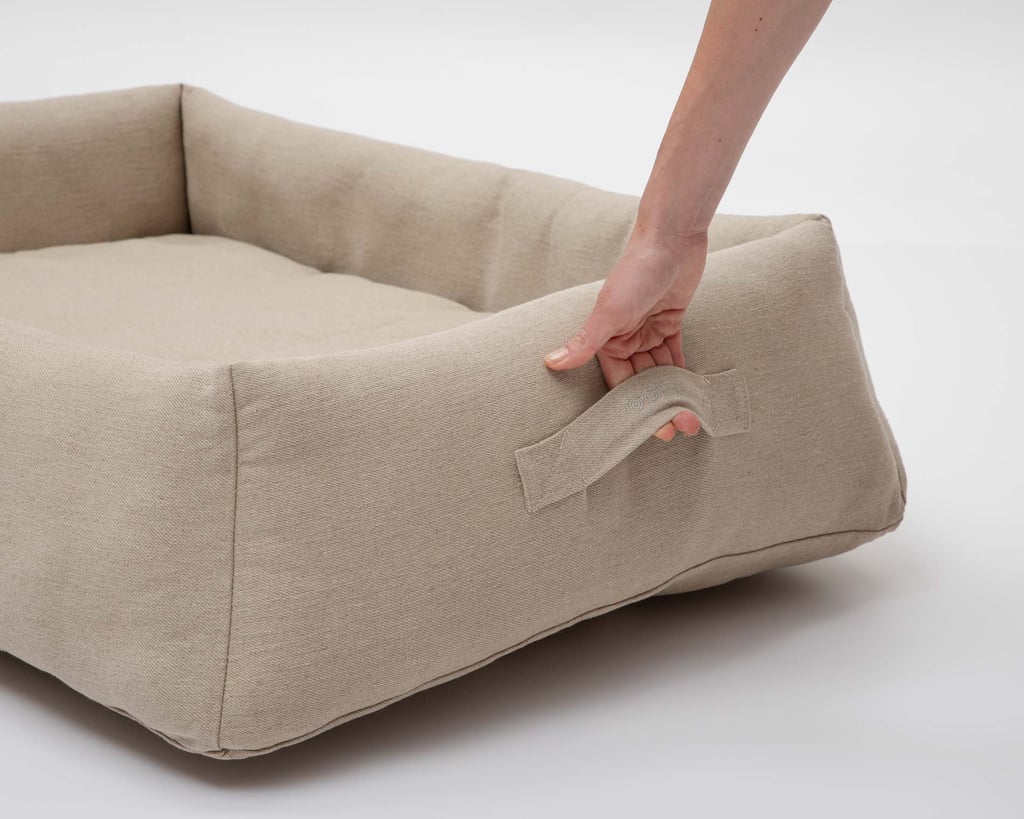 lit pour chien en laine avec une poignée saisie par une main