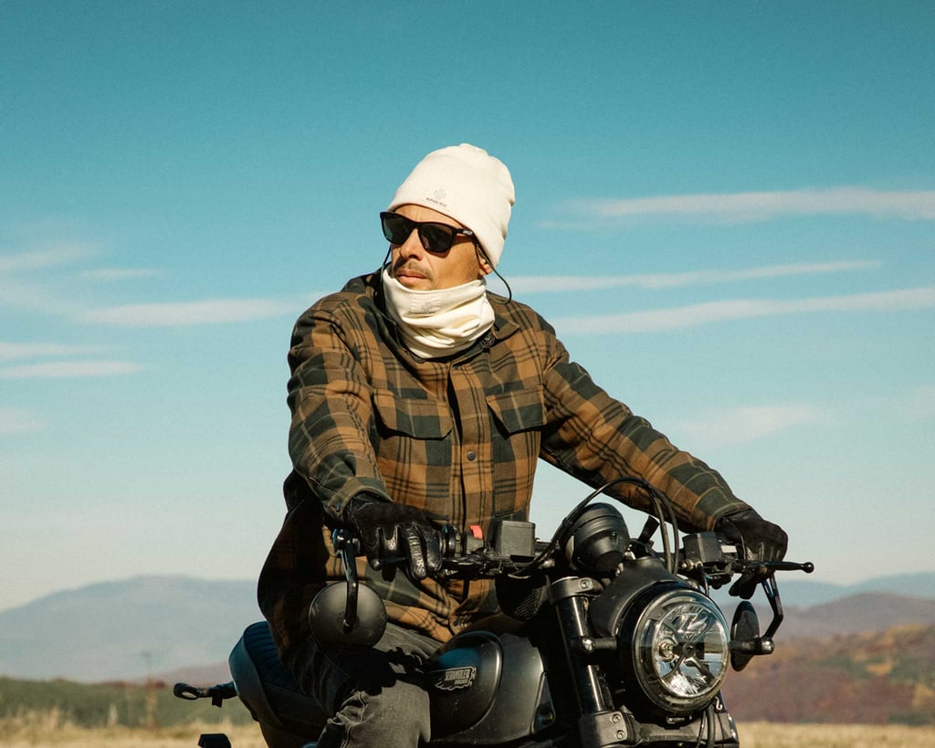man with sunglasses on a motorcycle with nomad heat beanie and neck gaiter with sky in the background