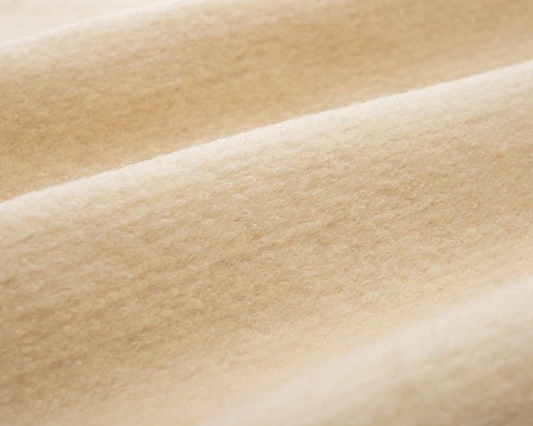 Nærbilde av teksturen på karakul-ullstoff fra Home of Wool