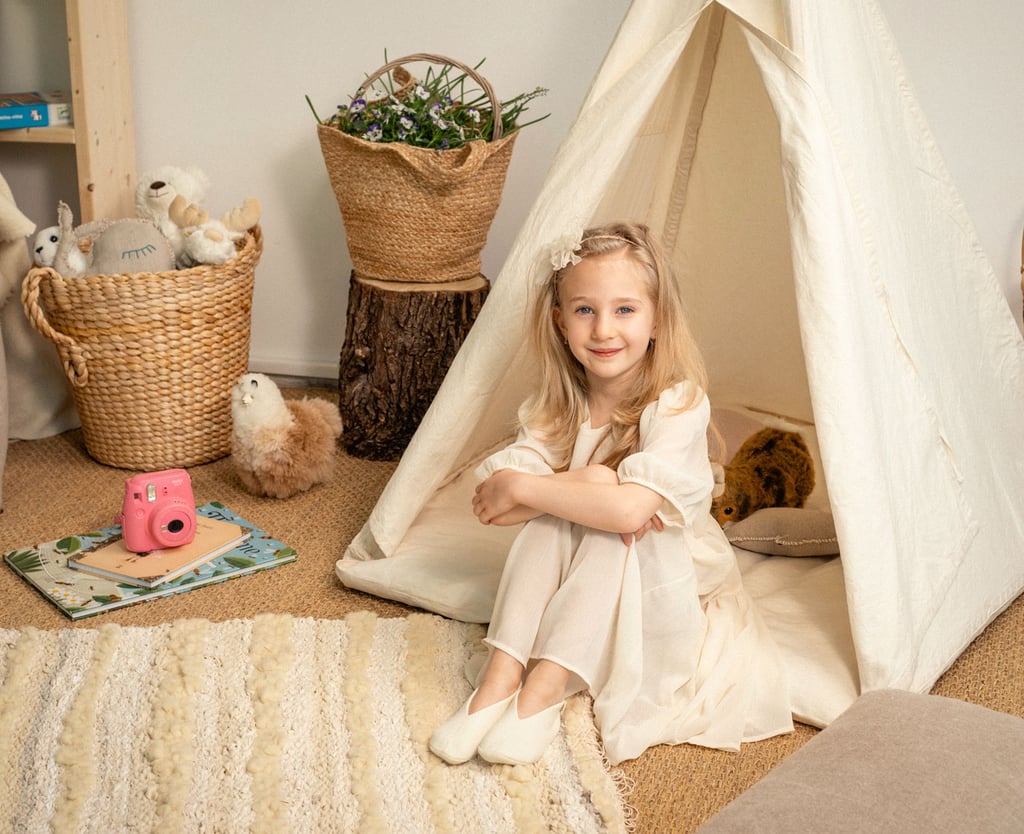 barn tipi tält i ett barnrum med en flicka framför det