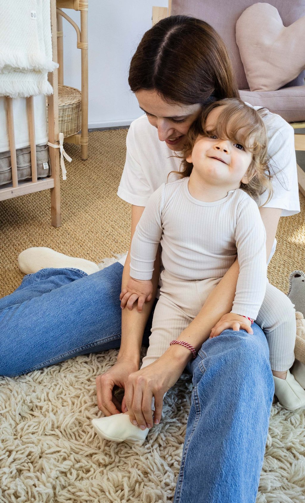 mom putting wool baby slippers on toddler in nursery