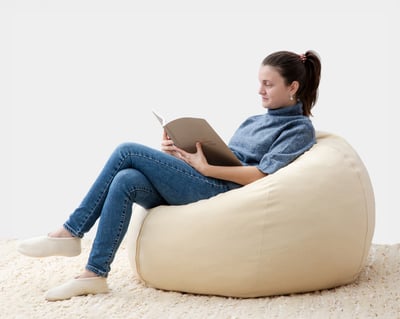 round wool bean bag chair with a woman sitting in it reading a book