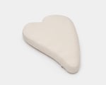 A heart-shaped wool pillow with a soft cotton cover in a light neutral color, designed for comfort with a simple, minimalist look.