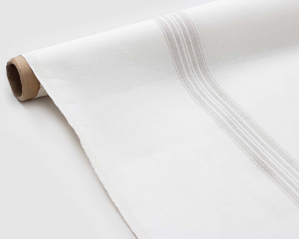 grey sriped linen fabric being rolled out flat on the floor